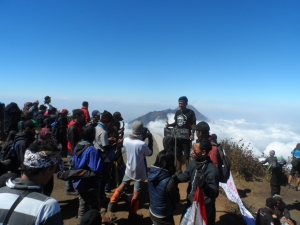 Para pendaki dengan tertib mengambil foto di atas Merbabu. Tampak Gunung Merapi di belakang.